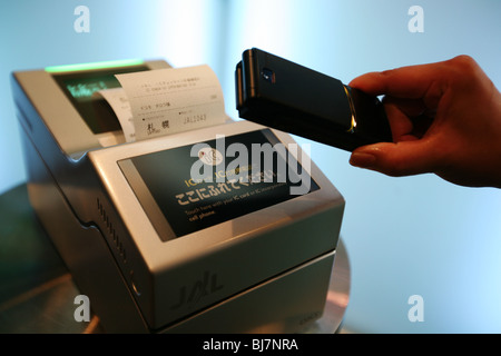 Utilizzando il telefono cellulare per effettuare il check-in per il volo aereo carta di imbarco, dimostrazione a DoCoMo 'Magic World' telefono mobile. Foto Stock