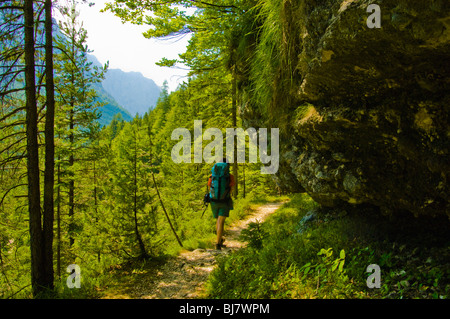 Escursionista sul sentiero sotto la sporgenza di roccia nella valle di Vrata, sulle Alpi Giulie, Slovenia Foto Stock