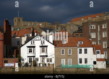 Pioggia nuvole raccogliere oltre le case di Whitby, anteriore accesa dai restanti raggi di sole prima del diluvio Foto Stock