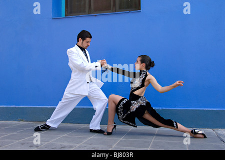 Due professionale Tango danzatori vestiti in bianco e nero contro una normale parete blu a La Boca Buenos Aires, Spagna Foto Stock