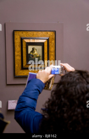 Donna turistica prendendo una fotografia digitale della Lacemaker dipinto di Vermeer, gen. Il museo del Louvre di Parigi. La Francia. Foto Stock