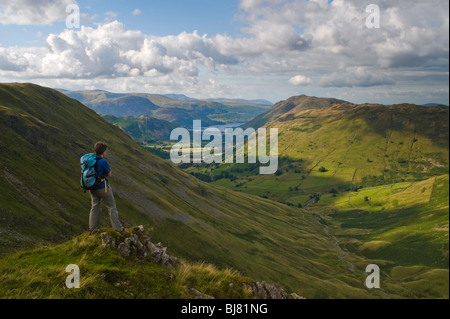 Walker sulla rupe Raven, guardando verso il basso pascolo Beck oltre Hartsop verso Ullswater, Lake District Foto Stock