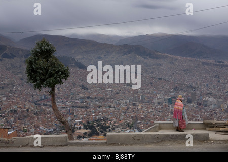 Donna indigena guardando fuori attraverso la paz come visto da el alto in Bolivia Foto Stock