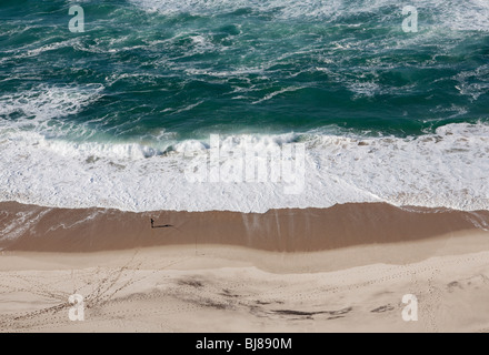 Una piccola persona in piedi su una grande spiaggia di sabbia a guardare l'oceano shot dal di sopra Foto Stock