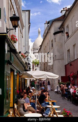 Cafe e scene di strada a Montmartre con cupole del Sacre Coeur oltre, Parigi Francia Foto Stock