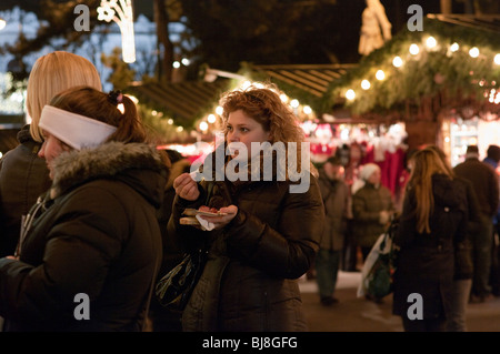 Giovani dai capelli ricci donna mangia un frankfurter a Rathaus Mercatini di Natale a Vienna Austria Foto Stock