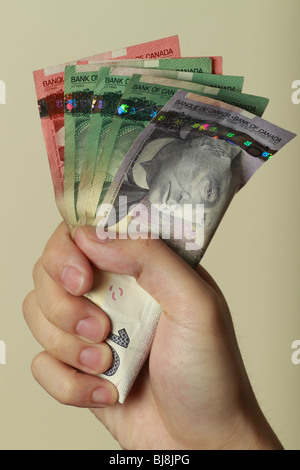 Un ritratto fotografico di stile di una mano di un uomo in un pugno tenendo un fan della Canadian cinquanta, venti e dieci le fatture del dollaro Foto Stock