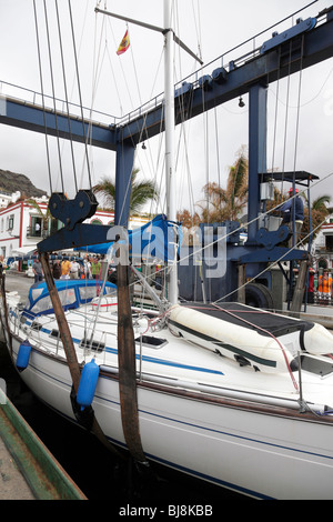 Yacht sollevato al di fuori dell'oceano da un paranco mobile nella marina di Puerto de Mogan gran canaria Foto Stock