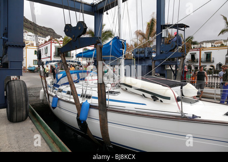 Yacht sollevato al di fuori dell'oceano da un paranco mobile nella marina di Puerto de Mogan gran canaria Foto Stock