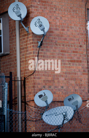 DirecTV e la rete del piatto delle antenne su un edificio di appartamenti. Foto Stock