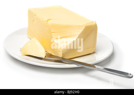 Pezzo di burro sulla piastra bianca con il coltello. Sfondo bianco e messa a fuoco poco profonde. Foto Stock