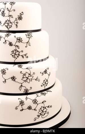 Elegante quattro tiered torta con nastro nero e nero intricate dei fiori di zucchero a forma di tubo di lavoro / la glassa Foto Stock