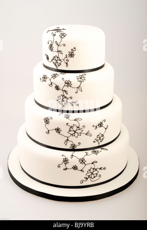 Elegante quattro tiered torta con nastro nero e nero intricate dei fiori di zucchero a forma di tubo di lavoro / la glassa Foto Stock