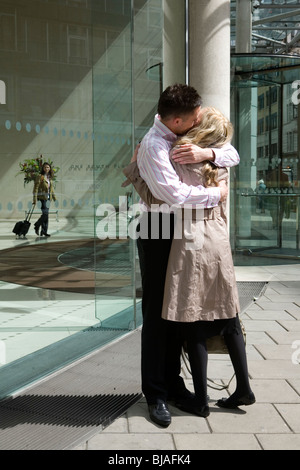 Coppia giovane abbracciando il vetro esterno edificio per uffici Foto Stock