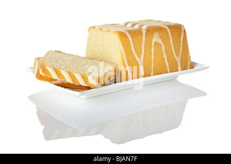 Torta al limone con glassa di zucchero e due fette sulla piastra bianca sulla superficie riflettente Foto Stock