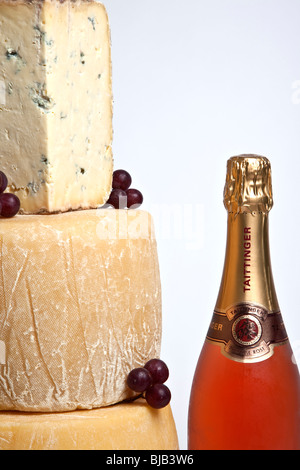 Una celebrazione torre di tutto il round di formaggi con una grande fetta di formaggio blu con una bottiglia di champagne rosato Foto Stock