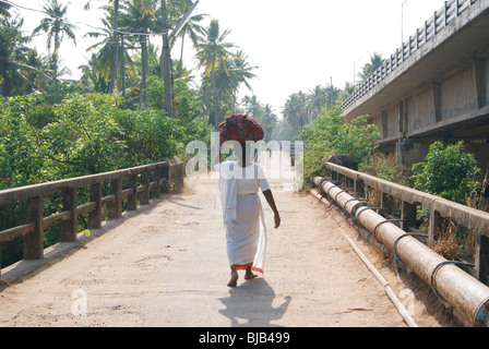 Povero vecchio nativa indiana le donne che trasportano vecchi panni come un bundle per il lavaggio in acqua di fiume.Una scena del villaggio dal Kerala, India Foto Stock