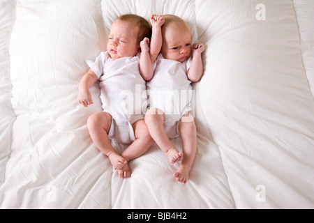 Twin Neonato Neonati affiancati sulla soffice coltre bianca Foto Stock