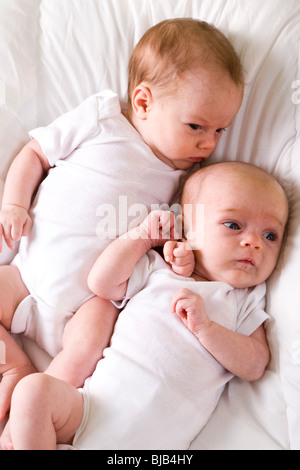 Un mese vecchio twin neonati affiancati sulla soffice coltre bianca Foto Stock