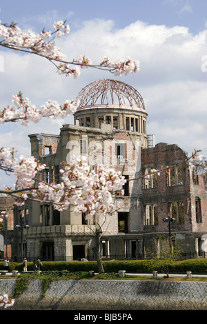 La cupola della bomba di Hiroshima, Giappone con la fioritura dei ciliegi in primo piano Foto Stock