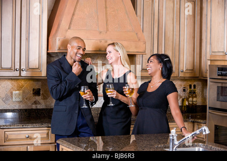 Mid-adult multi-razziale amici in chat cucina bere il vino Foto Stock