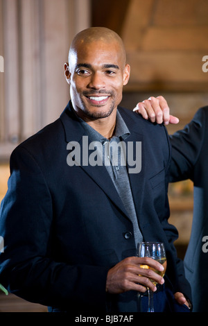 Afro-americano di successo Uomo in camicia gustando un bicchiere di vino Foto Stock