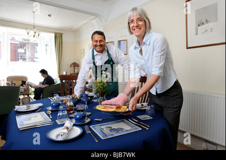 Una coppia che gestisce un bed and breakfast guesthouse servire la prima colazione di toast alla francese e la pancetta per un guest Foto Stock