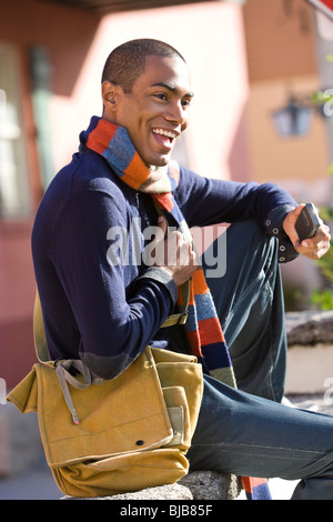 Bello stile afro-americano di giovane uomo seduto all'aperto Foto Stock