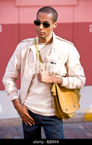 Bello stile afro-americano di giovane uomo sacco di contenimento in strada Foto Stock