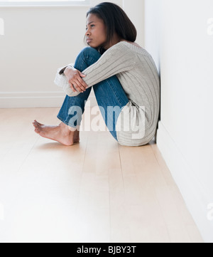 A piedi nudi razza mista donna seduta sul pavimento Foto Stock