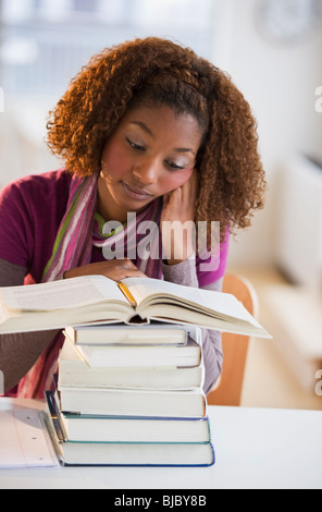 Razza mista donna che guarda la pila di libri Foto Stock