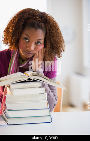 Razza mista donna che guarda la pila di libri Foto Stock