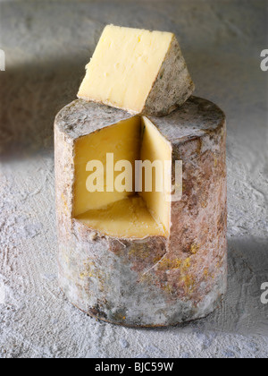 Tradizionale casa colonica britannico il formaggio Cheddar panno truckle legato con un cuneo da tagliare Foto Stock