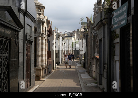 I turisti a piedi fila di vecchi mausolei in una strada a Recoleta cimitero Capital Federal Buenos Aires Foto Stock
