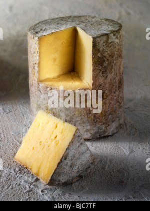 Tradizionale casa colonica britannico il formaggio Cheddar panno truckle legato con un cuneo da tagliare Foto Stock