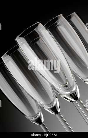 Foto studio di bicchieri da flauto da champagne vuoti angolati su sfondo graduato nero. Foto Stock