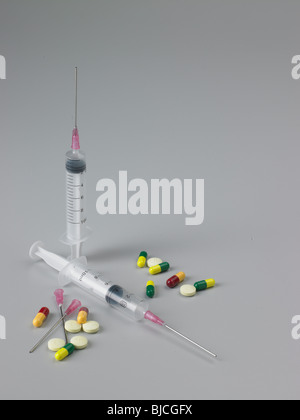 Siringhe e aghi con capsule e compresse con il rosso e il giallo pillole Foto Stock
