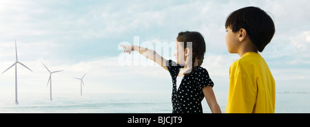 I bambini rivolti a turbine eoliche in distanza Foto Stock