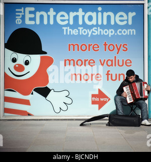 Un giovane busker suonando la fisarmonica, musicista di strada sulla street, Cardiff Wales UK Foto Stock