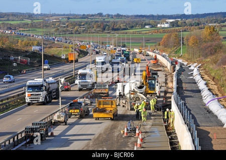 Ingegneria civile lavori stradali lavoratori edili e macchine che lavorano in cantiere M25 costruzione di un'autostrada a quattro corsie totale Essex paesaggio Inghilterra Regno Unito Foto Stock