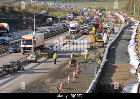 Ingegneria civile lavori stradali lavoratori edili e macchine che lavorano in cantiere M25 costruzione di un'autostrada a quattro corsie totale Essex paesaggio Inghilterra Regno Unito Foto Stock