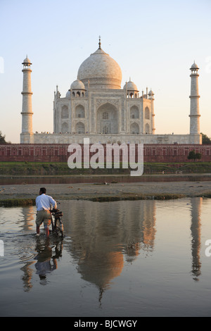 Uomo che porta bicicletta nel fiume Yamuna e la riflessione del Taj Mahal settimo meraviglie del mondo ; Agra ; Uttar Pradesh ; India Foto Stock