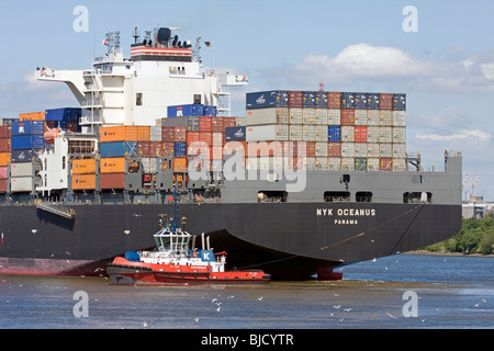 Contenitore con nave rimorchiatore in un porto, Germania Foto Stock