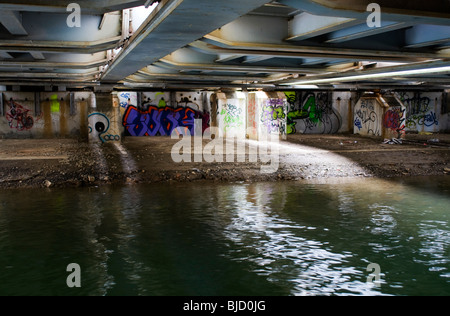 Una scena urbana di abbandono e degrado con graffiti sotto la linea ferroviaria principale passando sopra il canale di Oxford Foto Stock