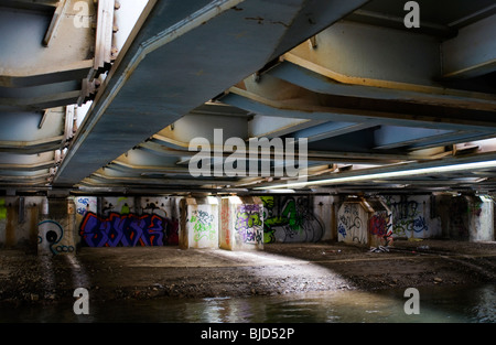 Una scena urbana di abbandono e degrado con graffiti sotto la linea ferroviaria principale passando sopra il canale di Oxford Foto Stock