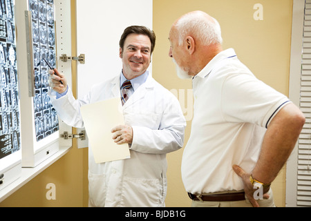 Medico o chiropratico per spiegare i risultati di una scansione TC della colonna vertebrale per il suo paziente che soffre di mal di schiena. Foto Stock