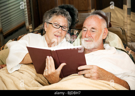 Coppia senior lettura insieme nel letto della loro casa a motore. Foto Stock