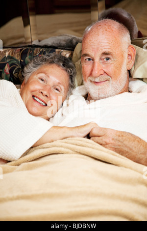 Felice coppia senior snuggling in letto. Vista verticale. Foto Stock