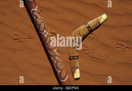 Boomerang e piccole didgeridoo sul rosso sabbia australiana. Nota piedi stampe di una lucertola. Ayers Rock, Territorio del Nord, l'Australia Foto Stock