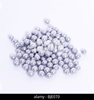 Un mucchio di sfere di argento per la decorazione delle torte su sfondo bianco Foto Stock
